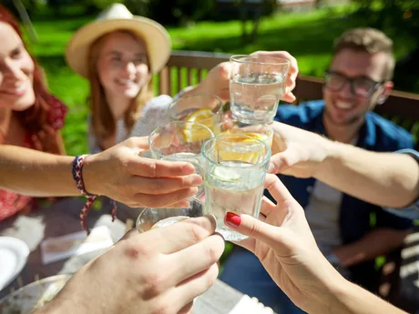 Friends raising glasses of water together at an outdoor table
