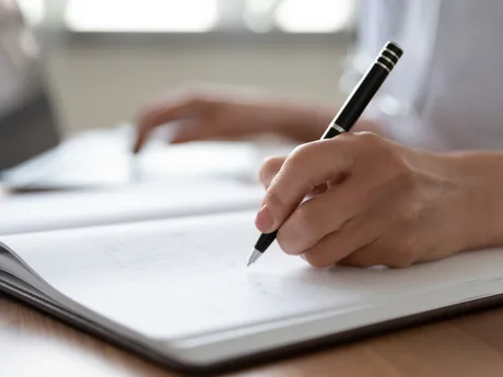 A physician writing notes at a desk