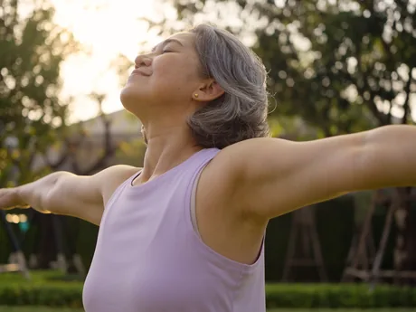 A woman outdoors at sunset with her arms open